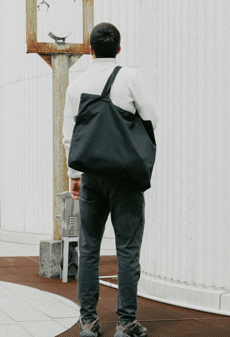 Rear view of Nectrum RPET tote in city use: model carrying laptop, groceries, and gym gear